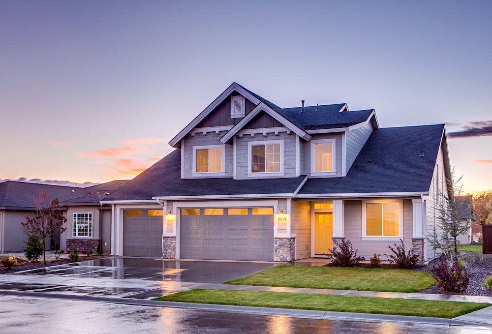 Home in neighborhood with lights on at dusk